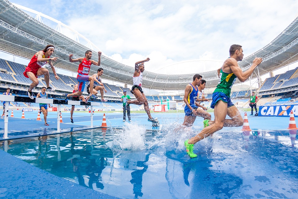 Sportowcy podczas zawodów przeskakują przez przeszkodę do wody. Bieganie przetrenowanie superkompensacja