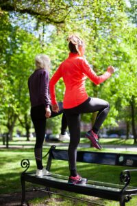 dwie kobiety seniorki ćwiczą w parku na ławce
